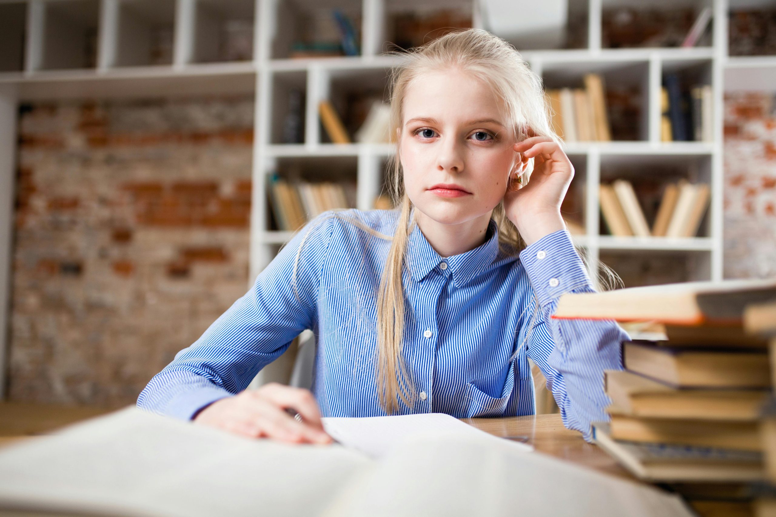Je déteste mes études, que faire ? 4 A young woman with blond hair studying at a table piled with books.