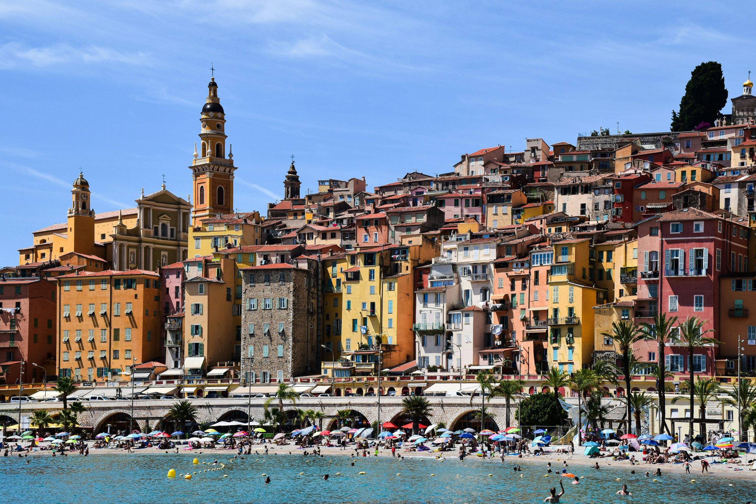 Vibrant buildings overlooking a lively beach in sunny Menton, Provence-Alpes-Côte d'Azur.