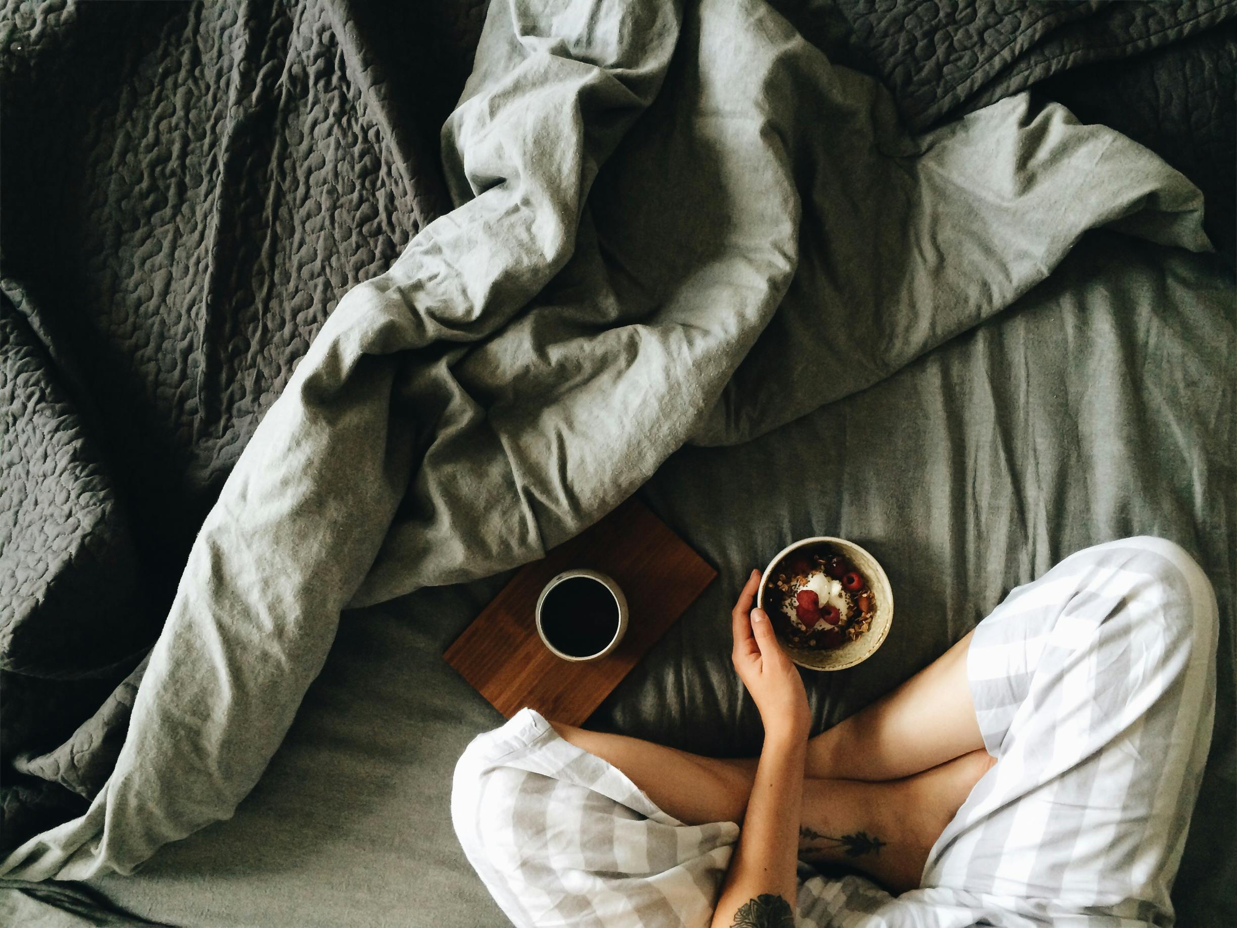 A peaceful morning scene featuring a woman enjoying breakfast and coffee in bed.
