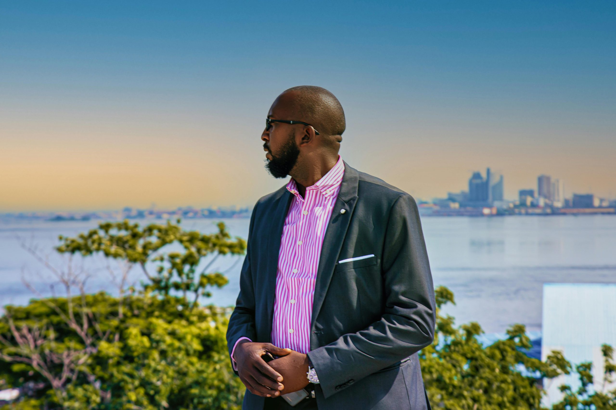 A bearded man in a suit gazes over the Brazzaville skyline with confidence and style.