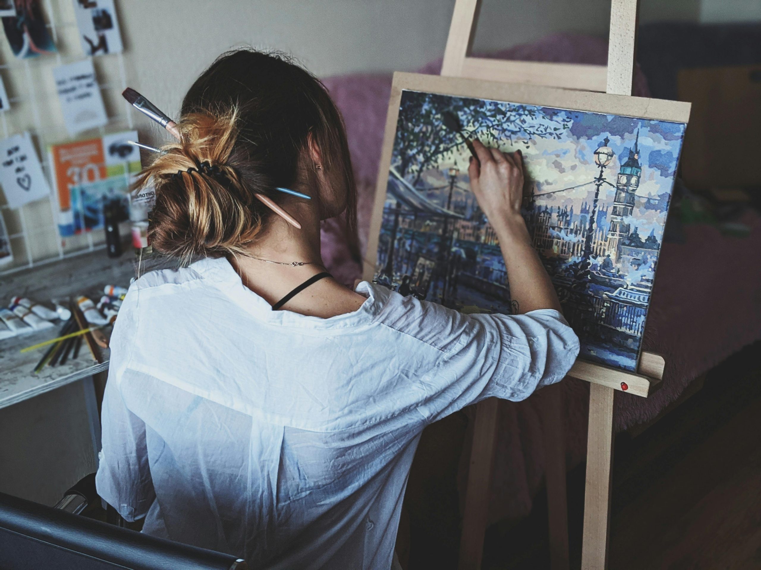 An artist captures a London cityscape on canvas at an indoor studio.