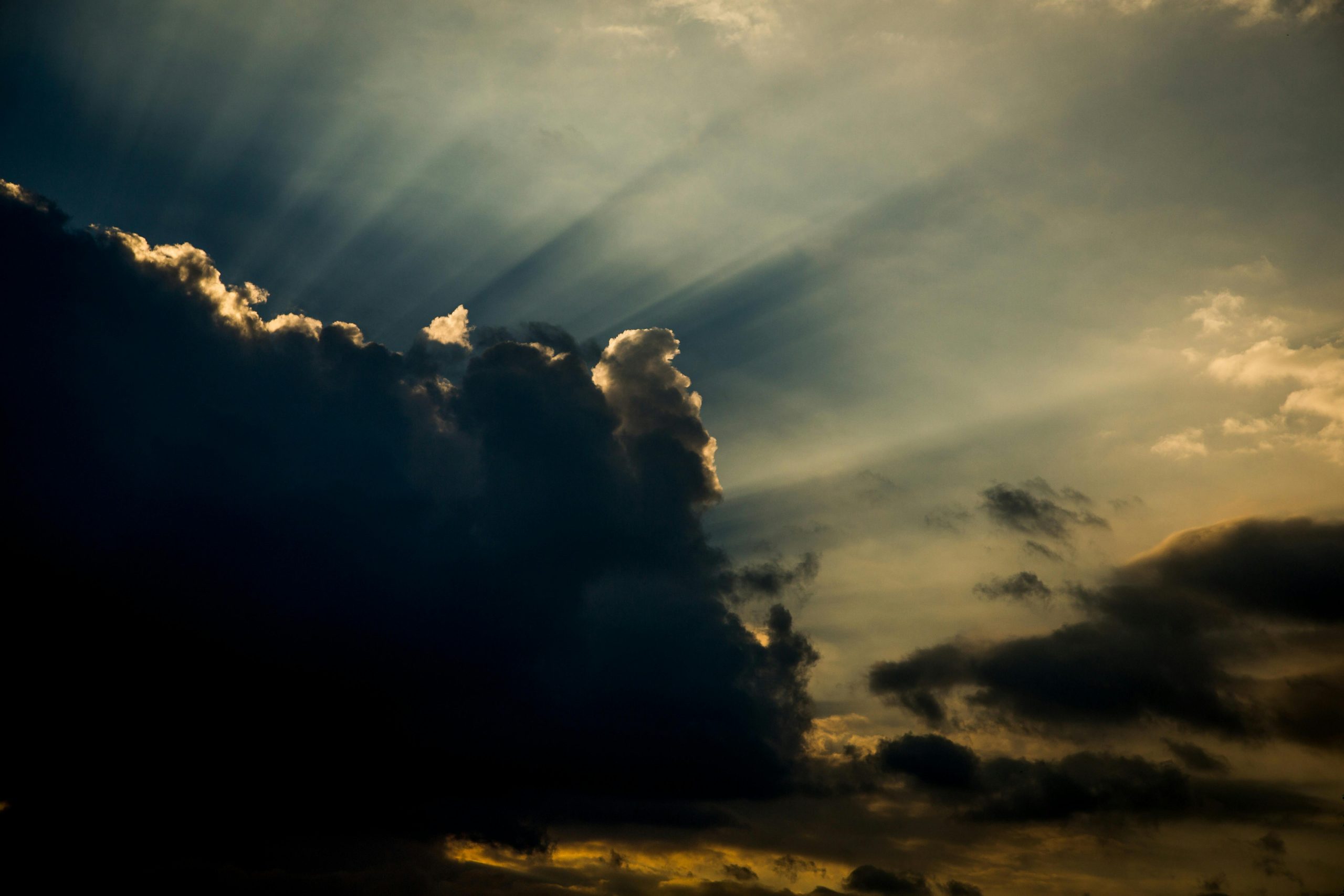 Dark clouds with dramatic sunbeams and a golden twilight sky, creating a sense of hope.