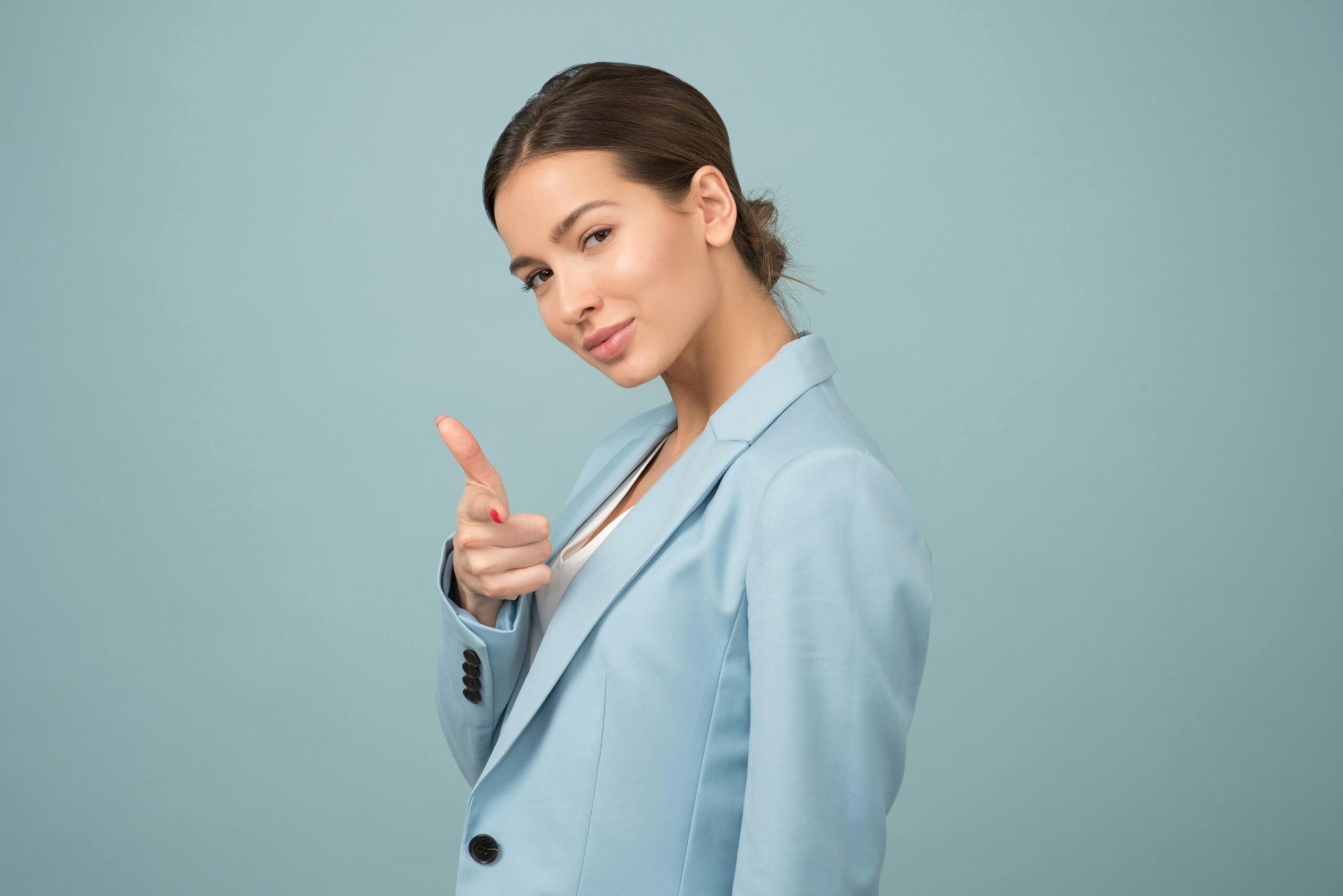Comment se vendre soi-même : poser les bases sans se renier 4 A young woman in a blue suit exhibits confidence with a relaxed pose against a blue background.