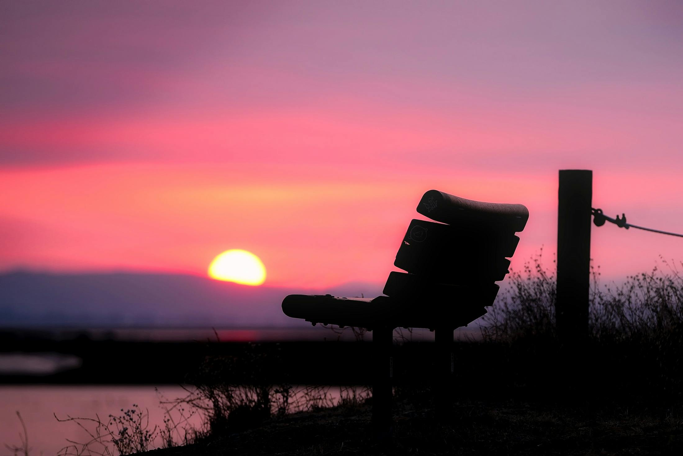 Serene silhouette of a bench facing a beautiful sunset sky, evoking relaxation and peace.