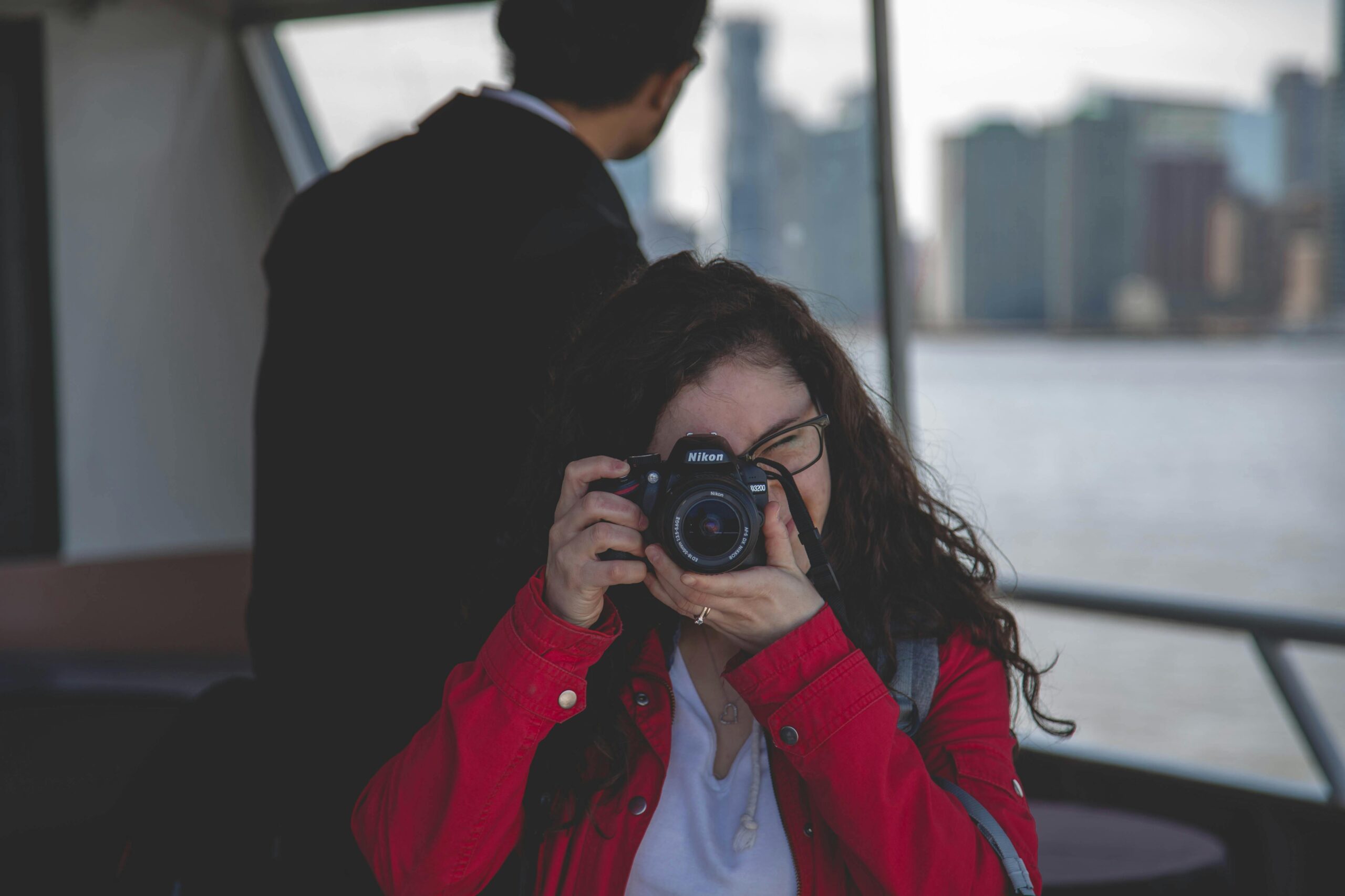 Woman taking photos from a boat with city skyline view.