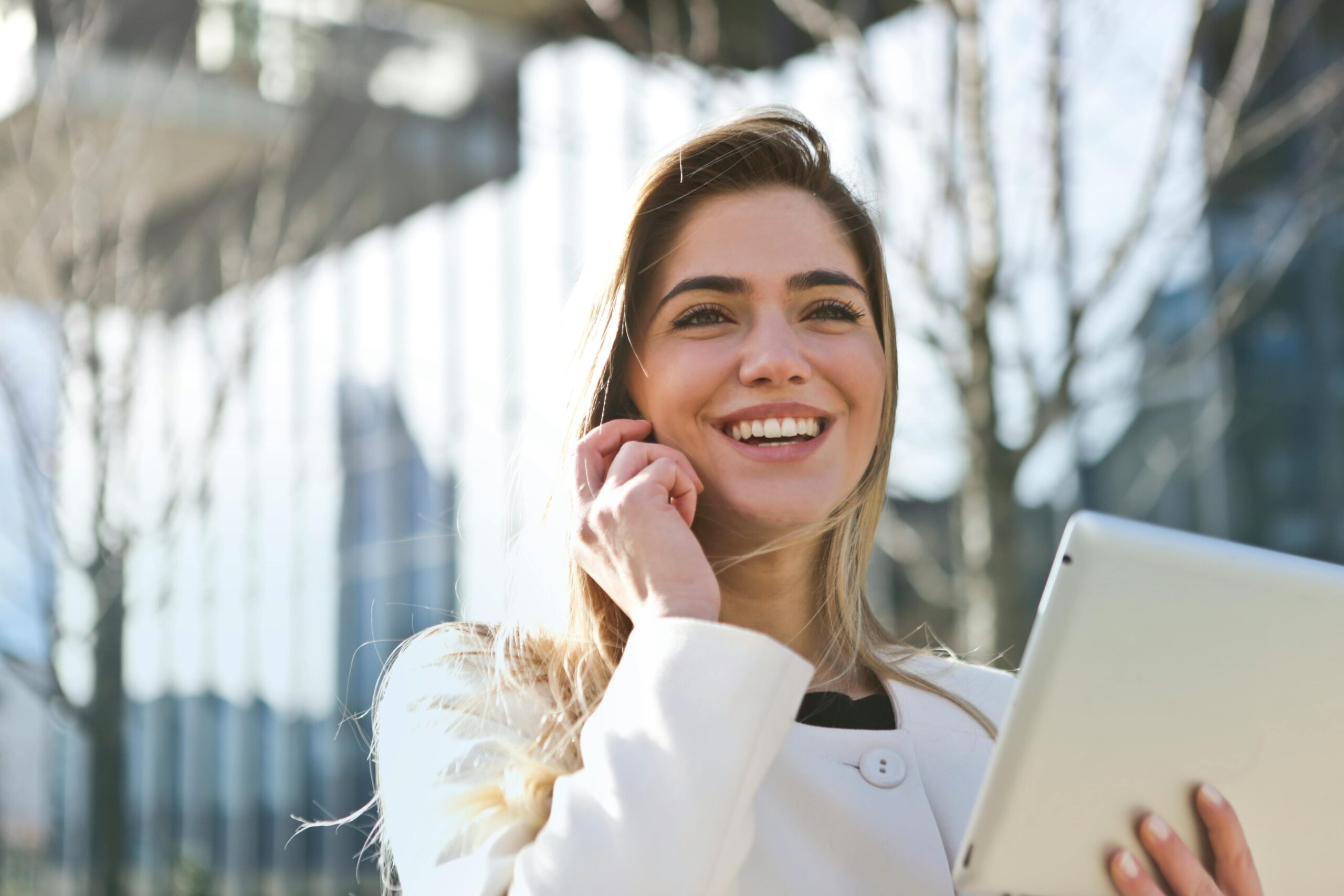 Blog business en ligne : un site pour comprendre, lancer et structurer un vrai business sur internet 2 Confident businesswoman using her tablet and phone, smiling outdoors in sunlight.