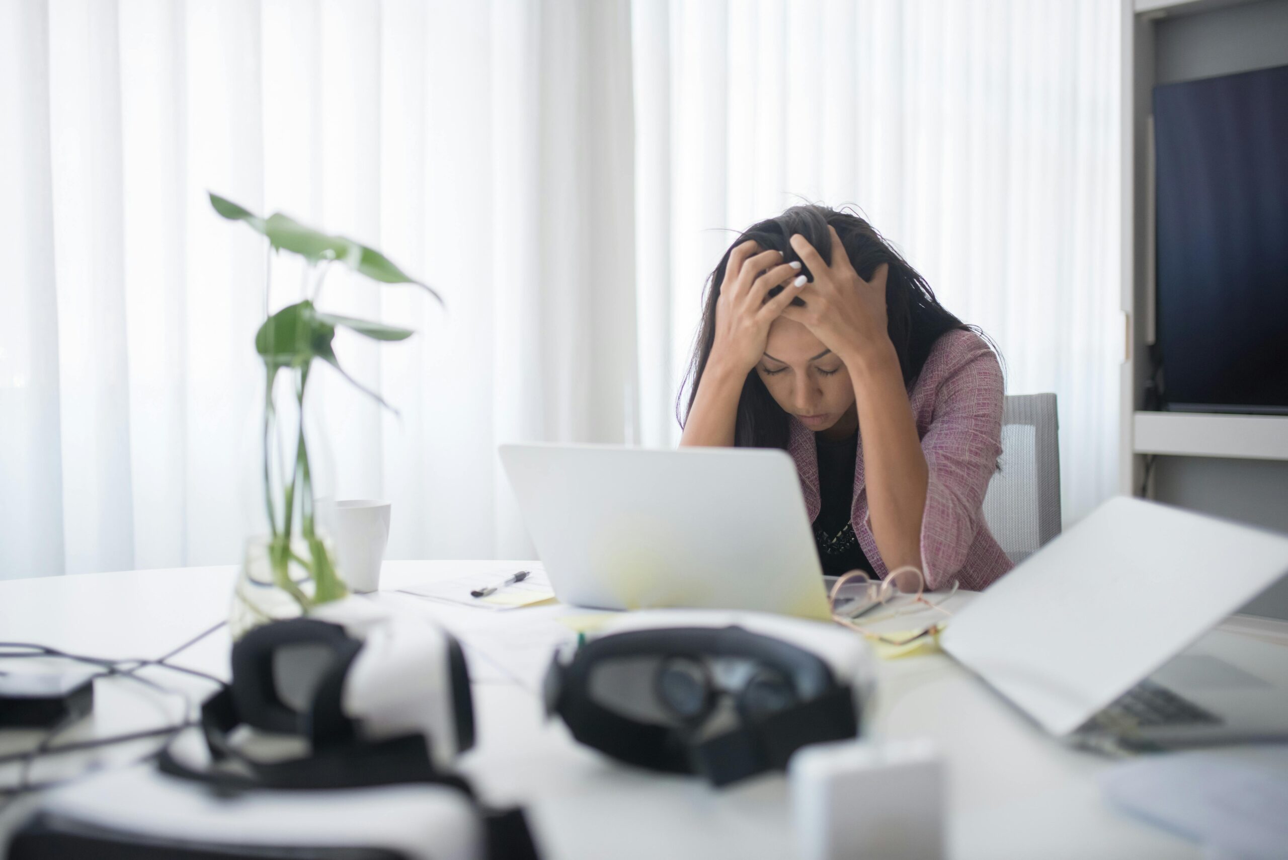 Comment dé-scaler son entreprise : la vraie méthode pour reprendre le contrôle (sans flinguer sa croissance) 4 Frustrated woman sitting at desk with laptop, showing stress in a modern office environment.