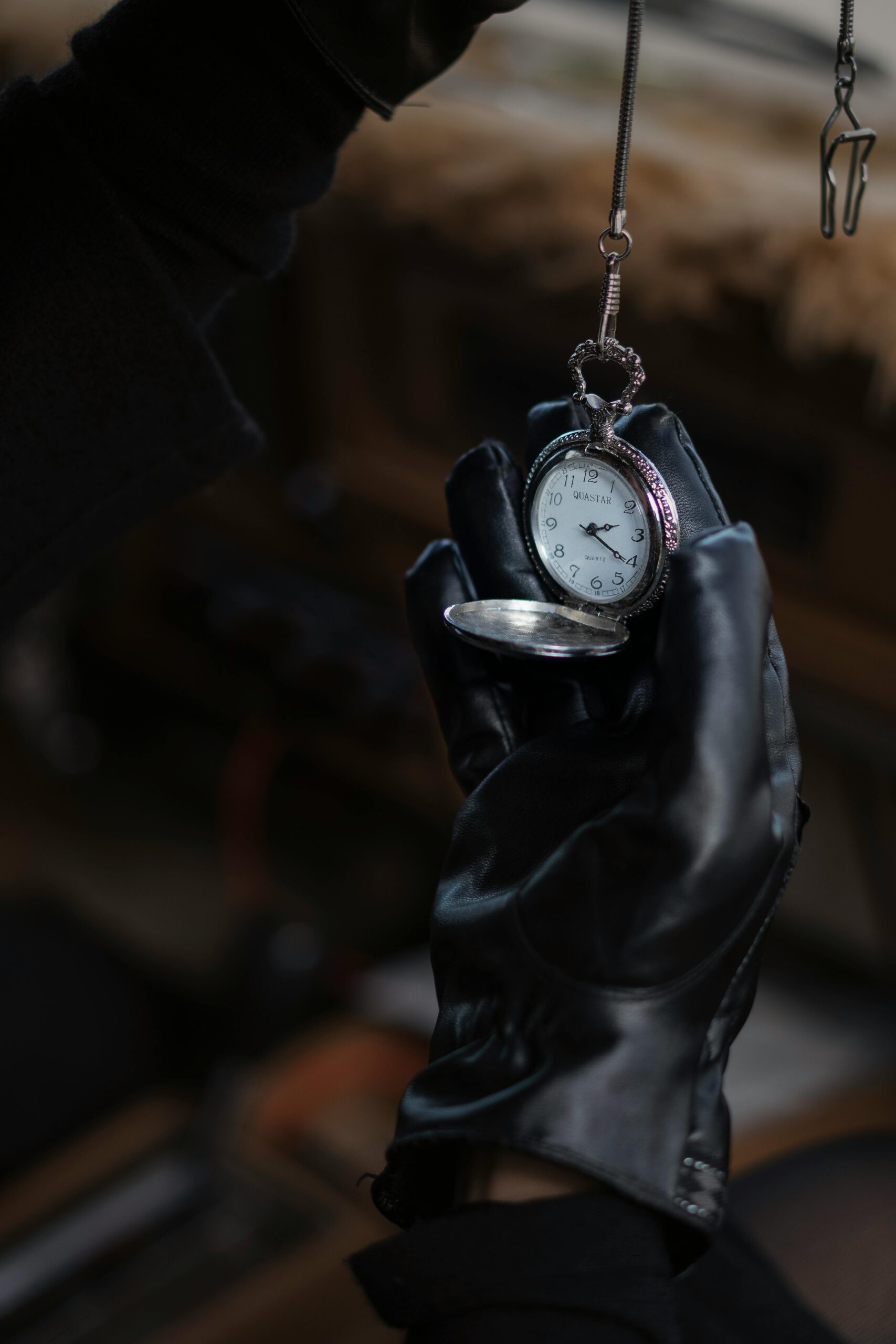 A leather-gloved hand holding an antique pocket watch, evoking nostalgia and elegance.