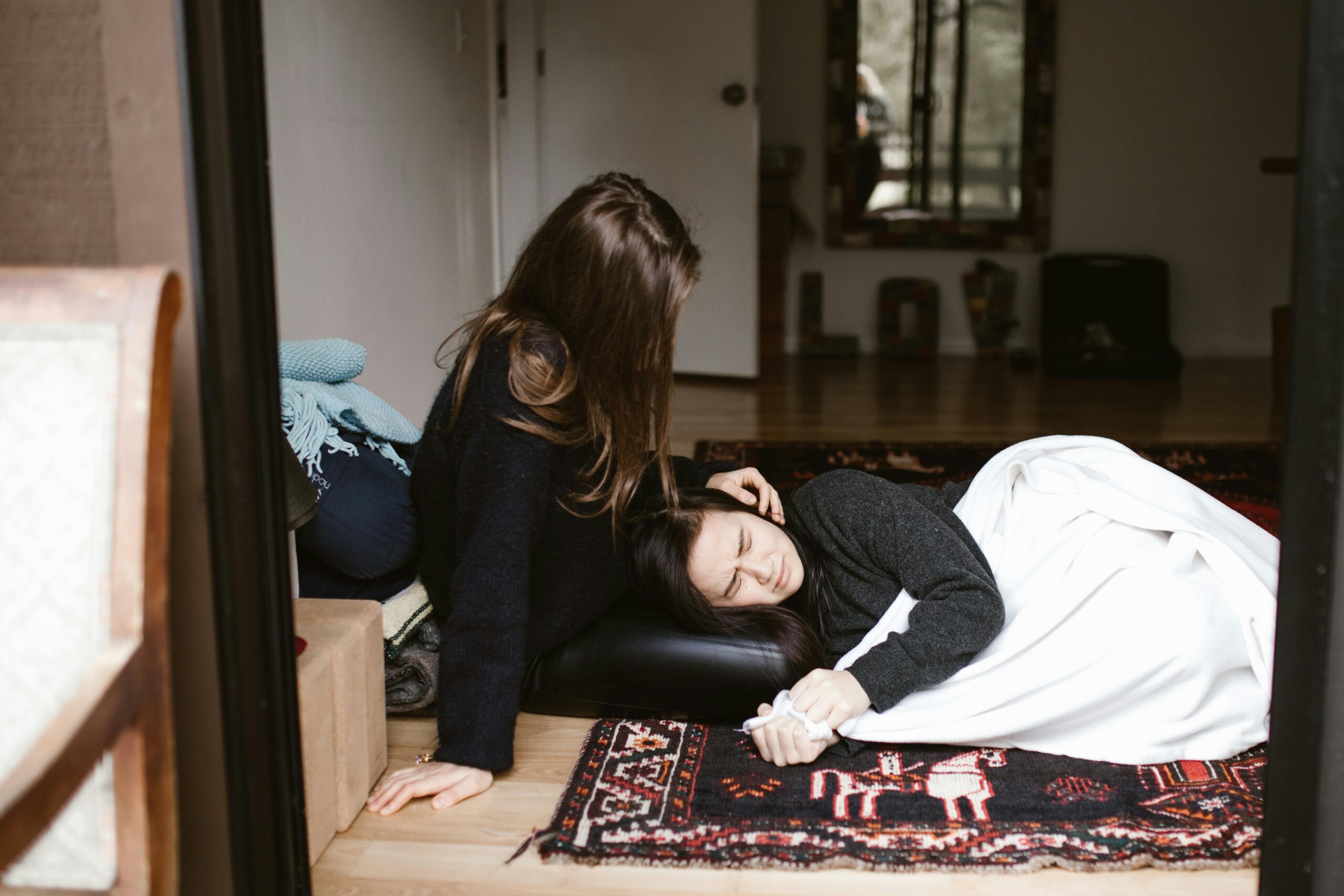 Tristesse inexpliquée : le signal caché du corps 2 A woman comforts another during an emotional moment indoors, evoking themes of empathy and support.
