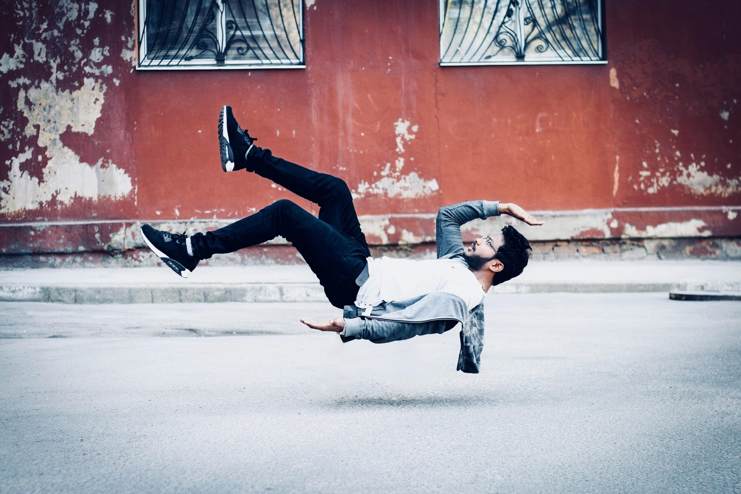 A man levitates in an urban setting, showcasing artistic photographic skills.