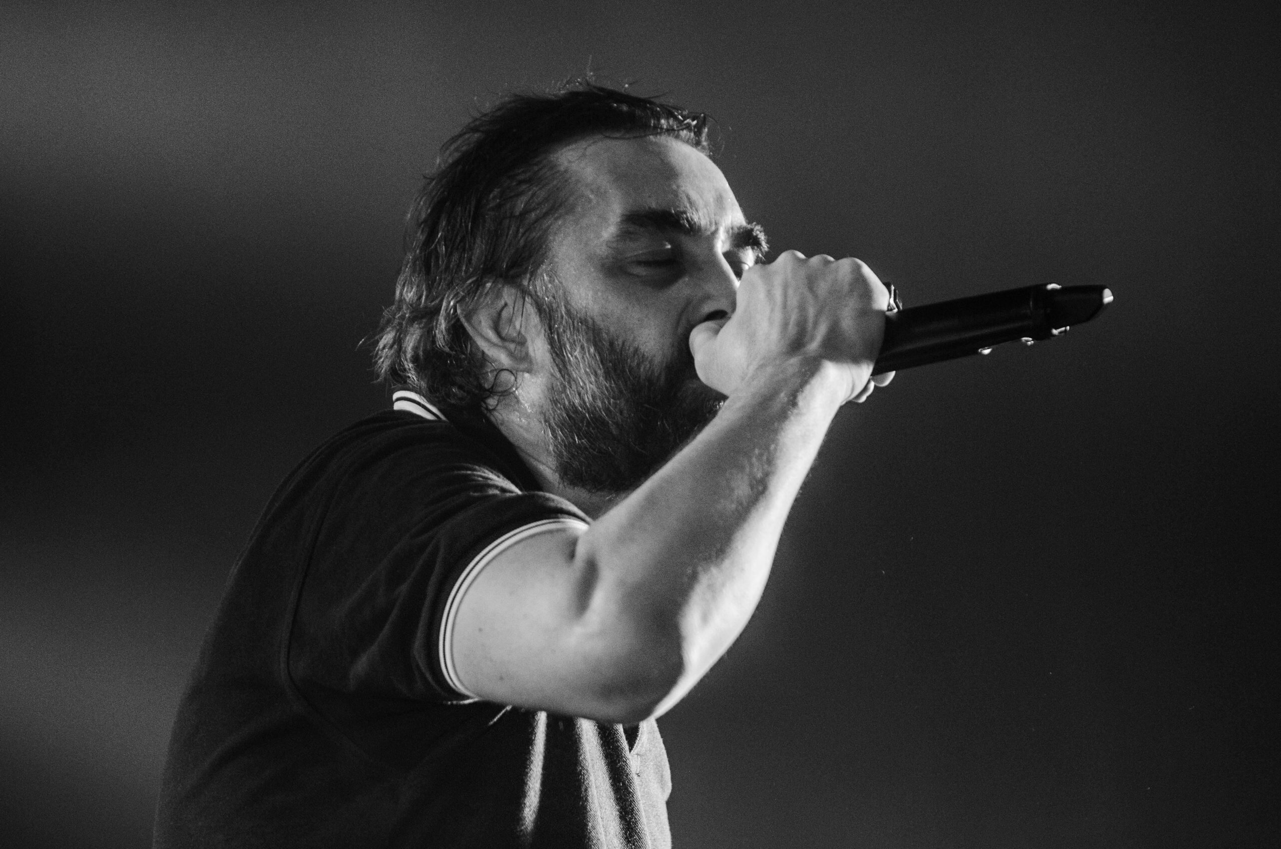 Monochrome close-up of a male singer passionately performing with a microphone.