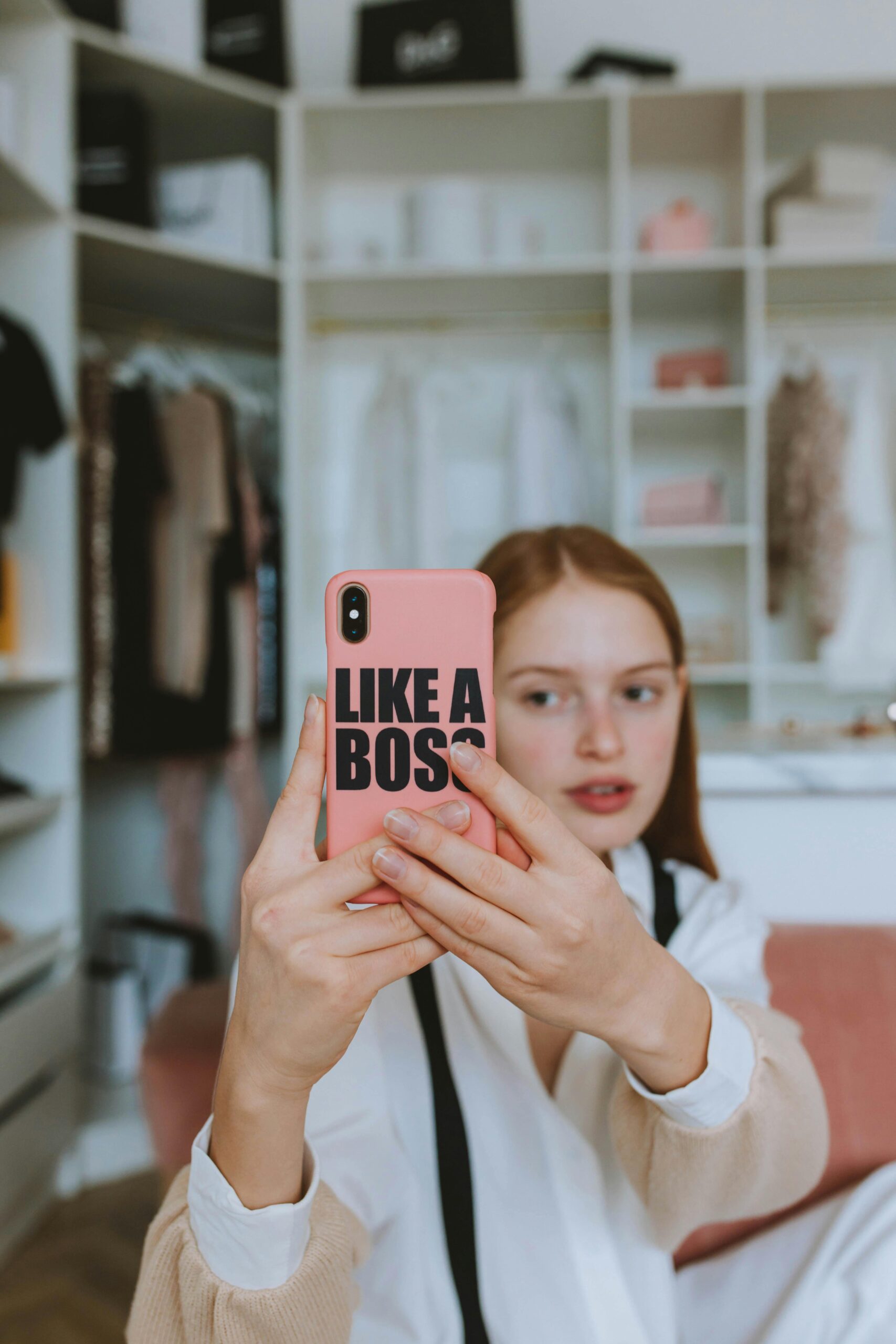 Teenage girl with ginger hair taking a selfie in a stylish wardrobe room. Modern lifestyle and fashion.