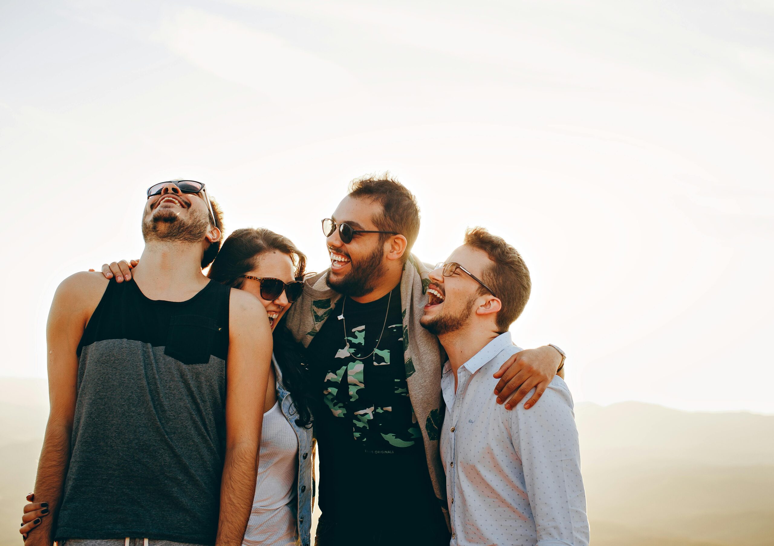 Créer une communauté SchoolMaker active pour ton business 2 A group of young adults laughing and enjoying time together outdoors under the sun.
