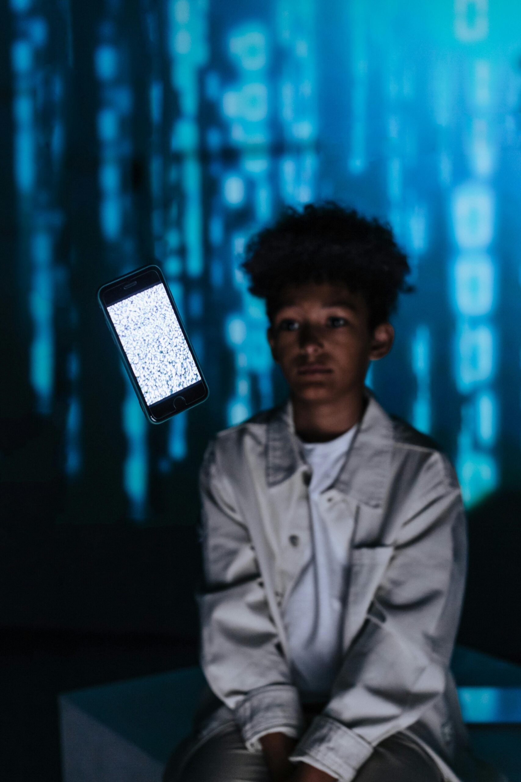 Young boy with floating phone in digital background, tech concept.