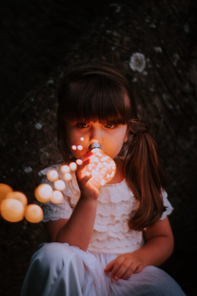 A young girl holds a lit bulb, creating a magical glow. Perfect for fantasy-themed imagery.