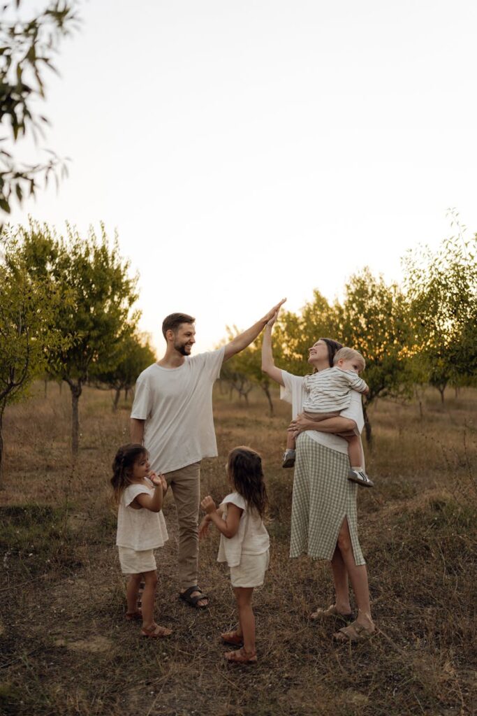 A joyful family of five sharing a moment in a serene outdoor setting during sunset.