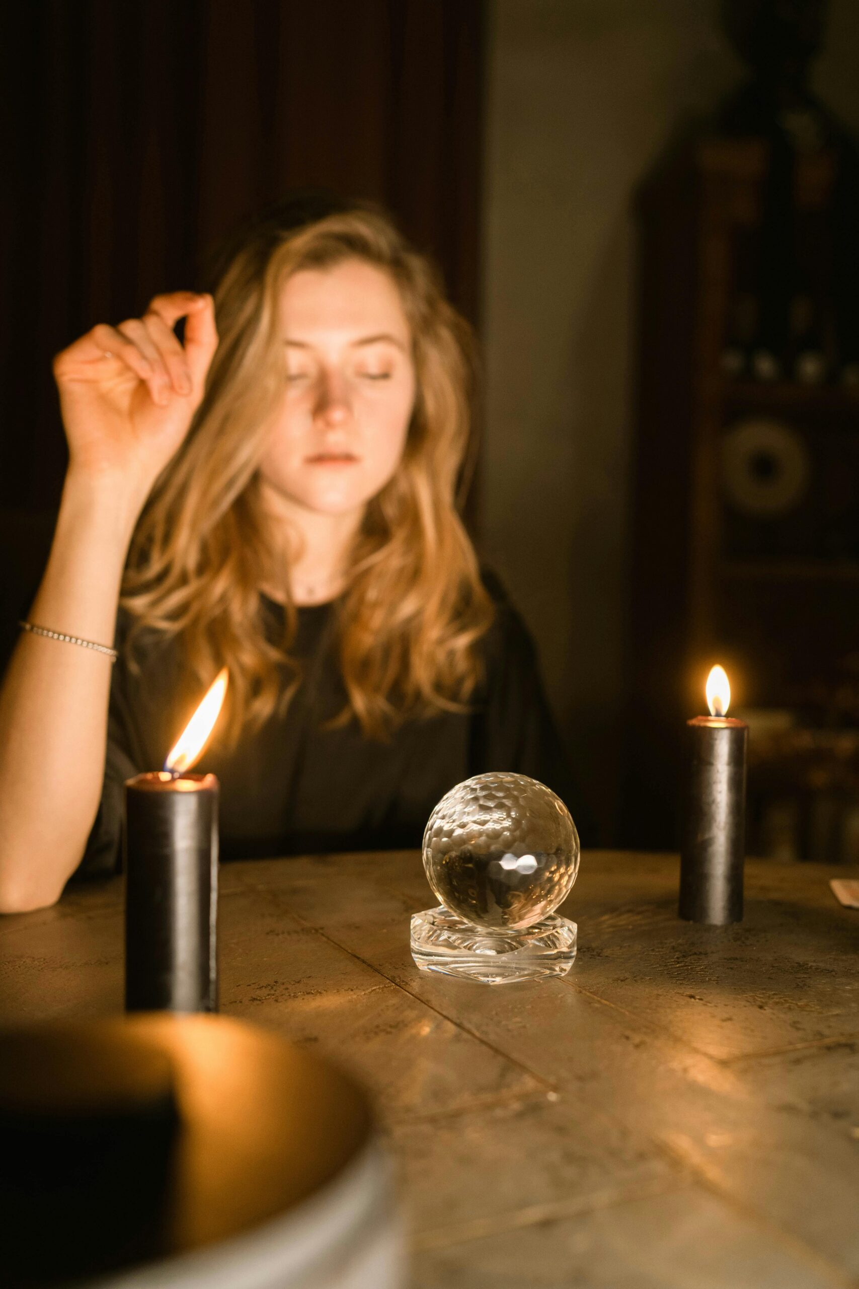 A woman engaged in a candle-lit ritual with a crystal ball, creating a mystical ambiance.