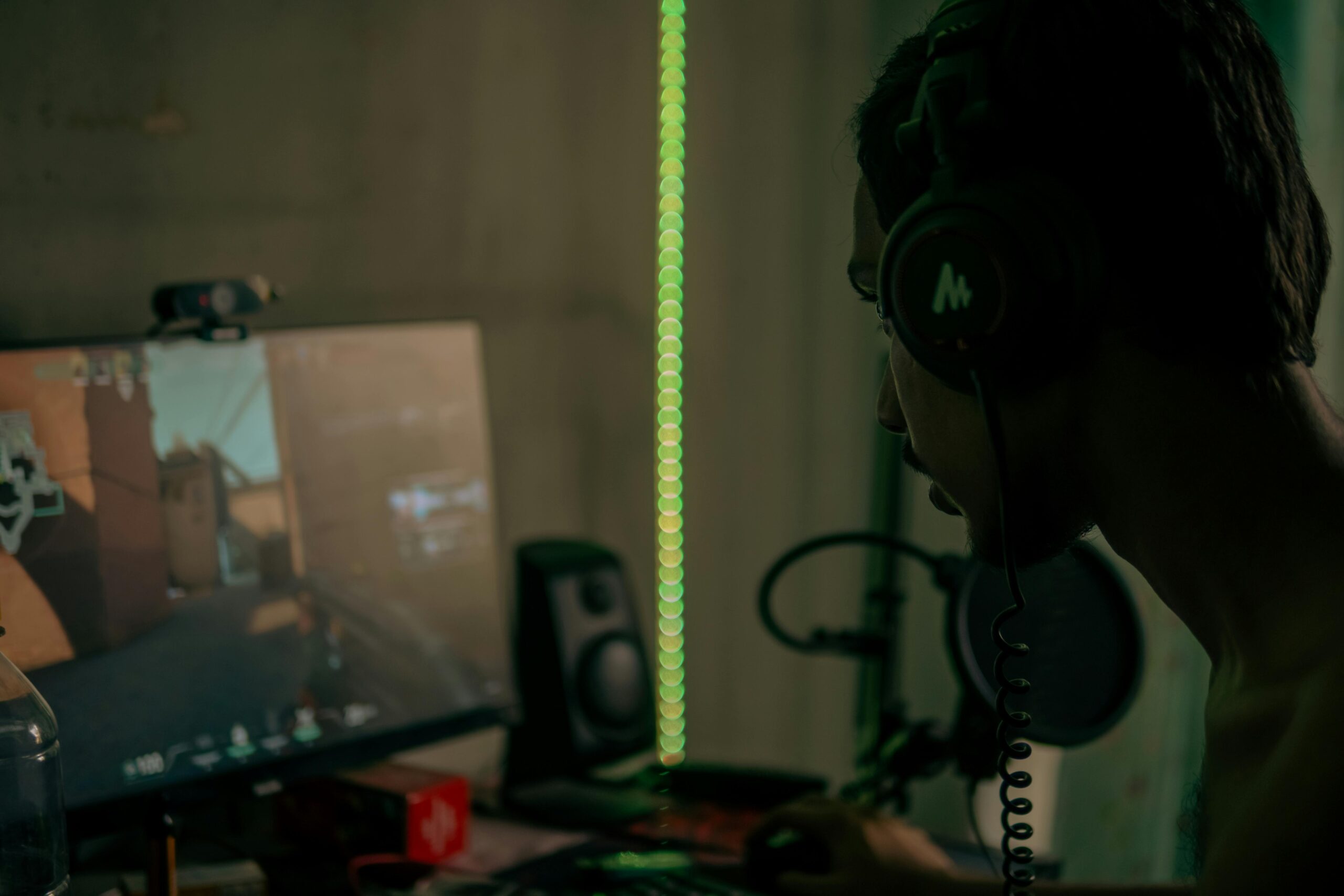 Focused gamer with headset playing a video game on a desktop computer indoors.