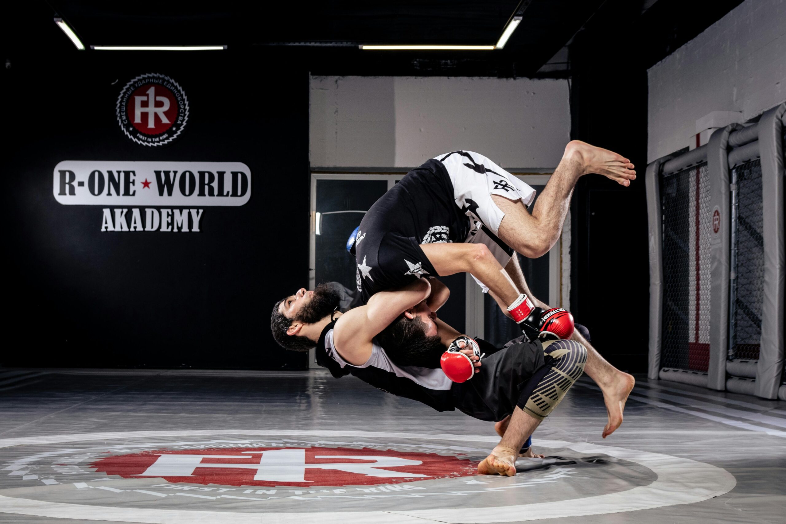 Two martial artists engaged in a high-impact sparring session at R-One World Academy.
