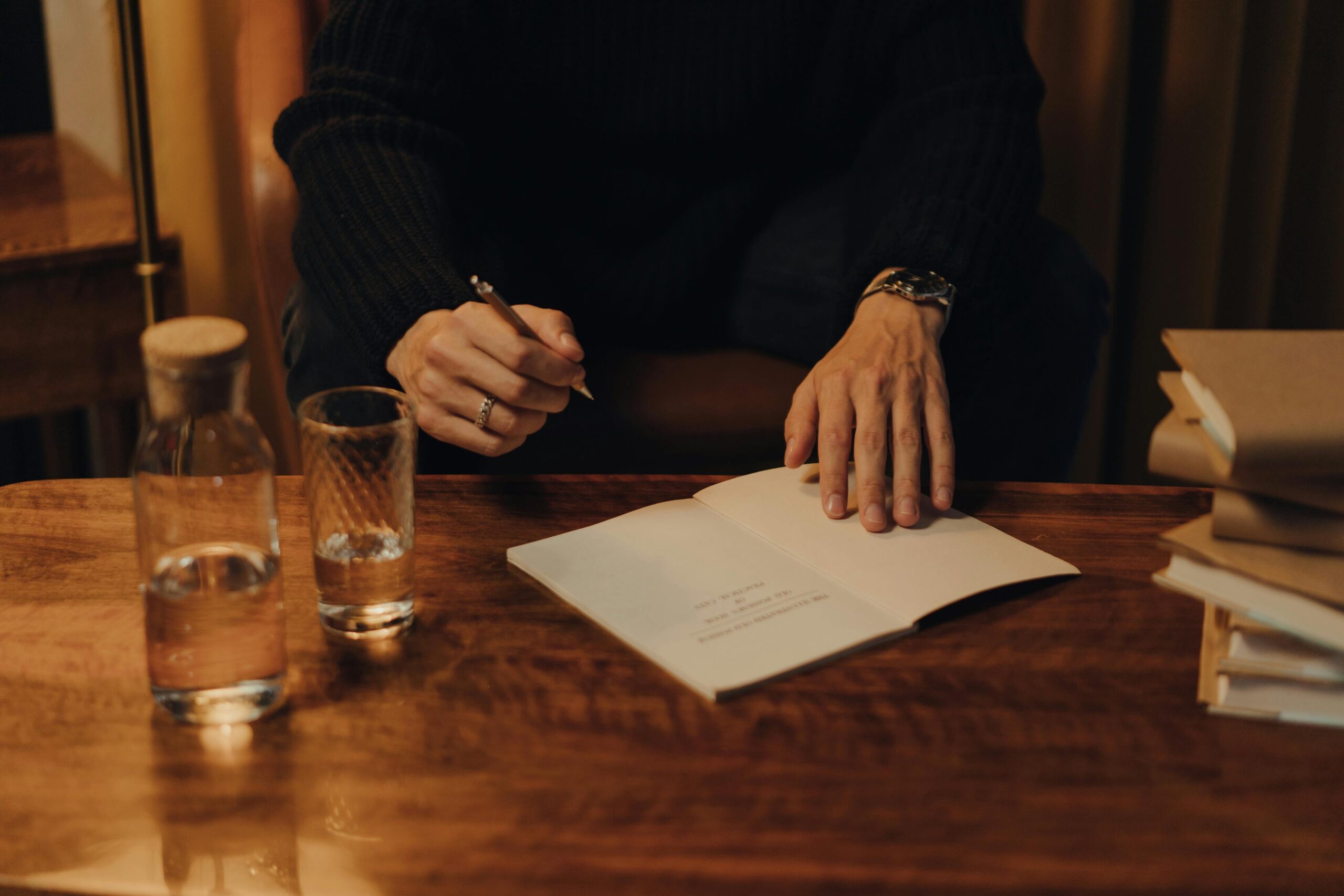 Les prête-plume célèbres : histoire, techniques, enjeux et grandes figures du ghostwriting 4 Man signing books during an intimate creative event in a cozy indoor setting.