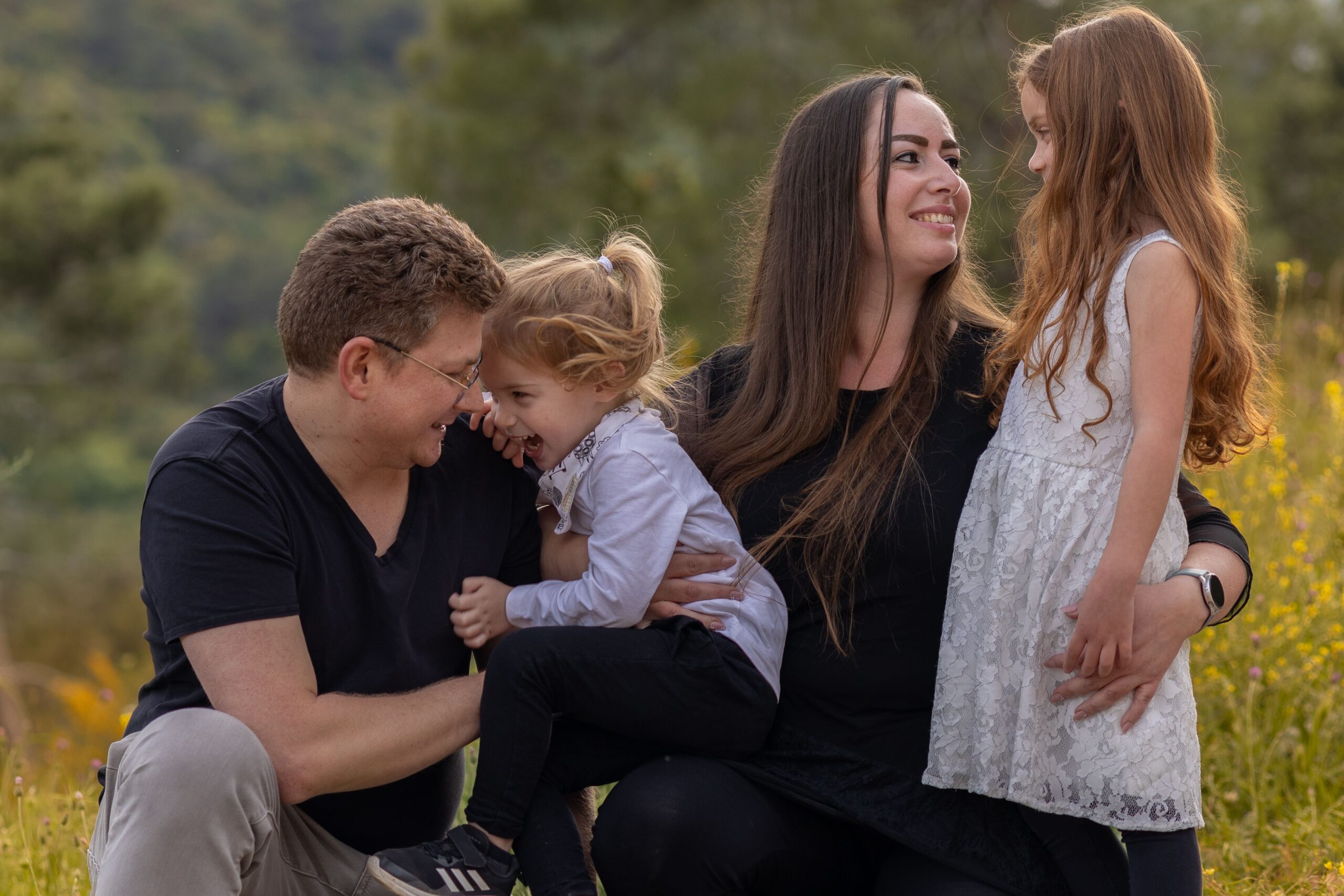 A joyful family enjoying a moment outdoors with their daughters.