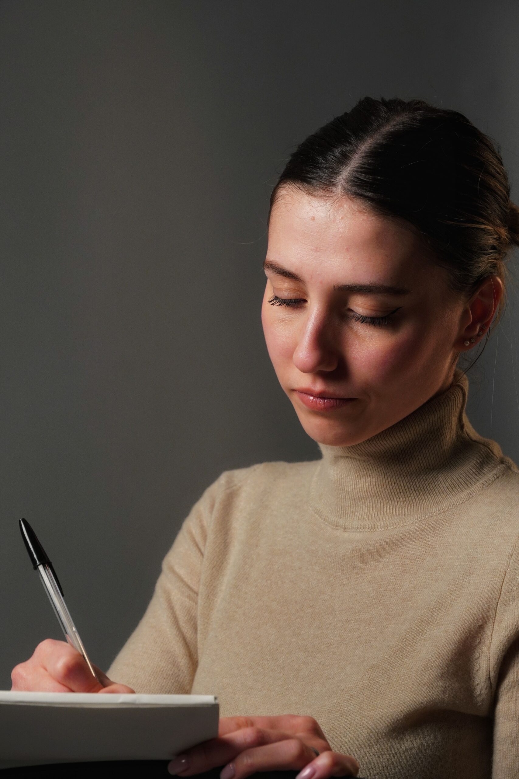 Portrait of a woman concentrating while writing on a notebook indoors.