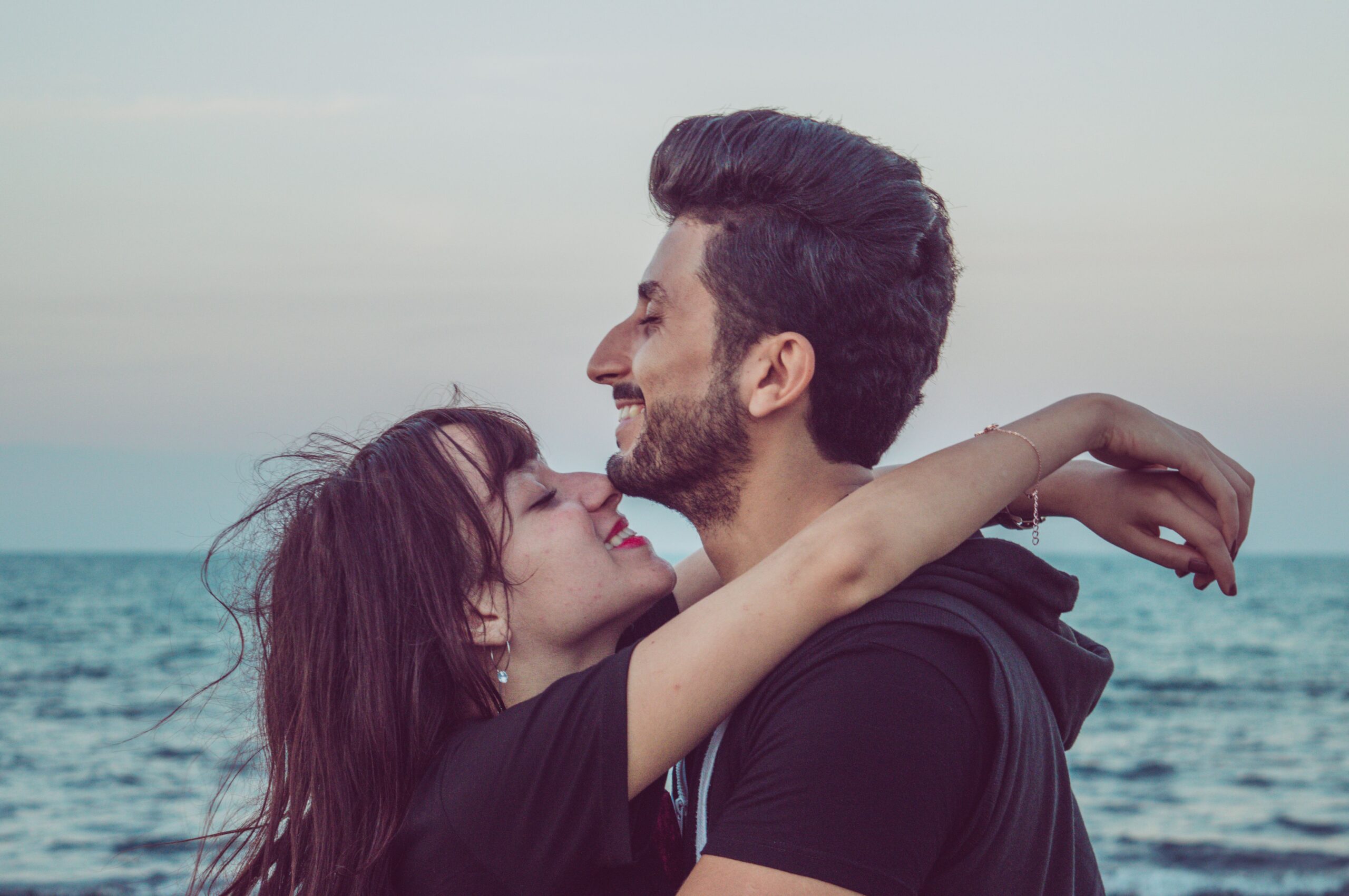 A couple embracing lovingly near the ocean, enjoying a peaceful moment together.