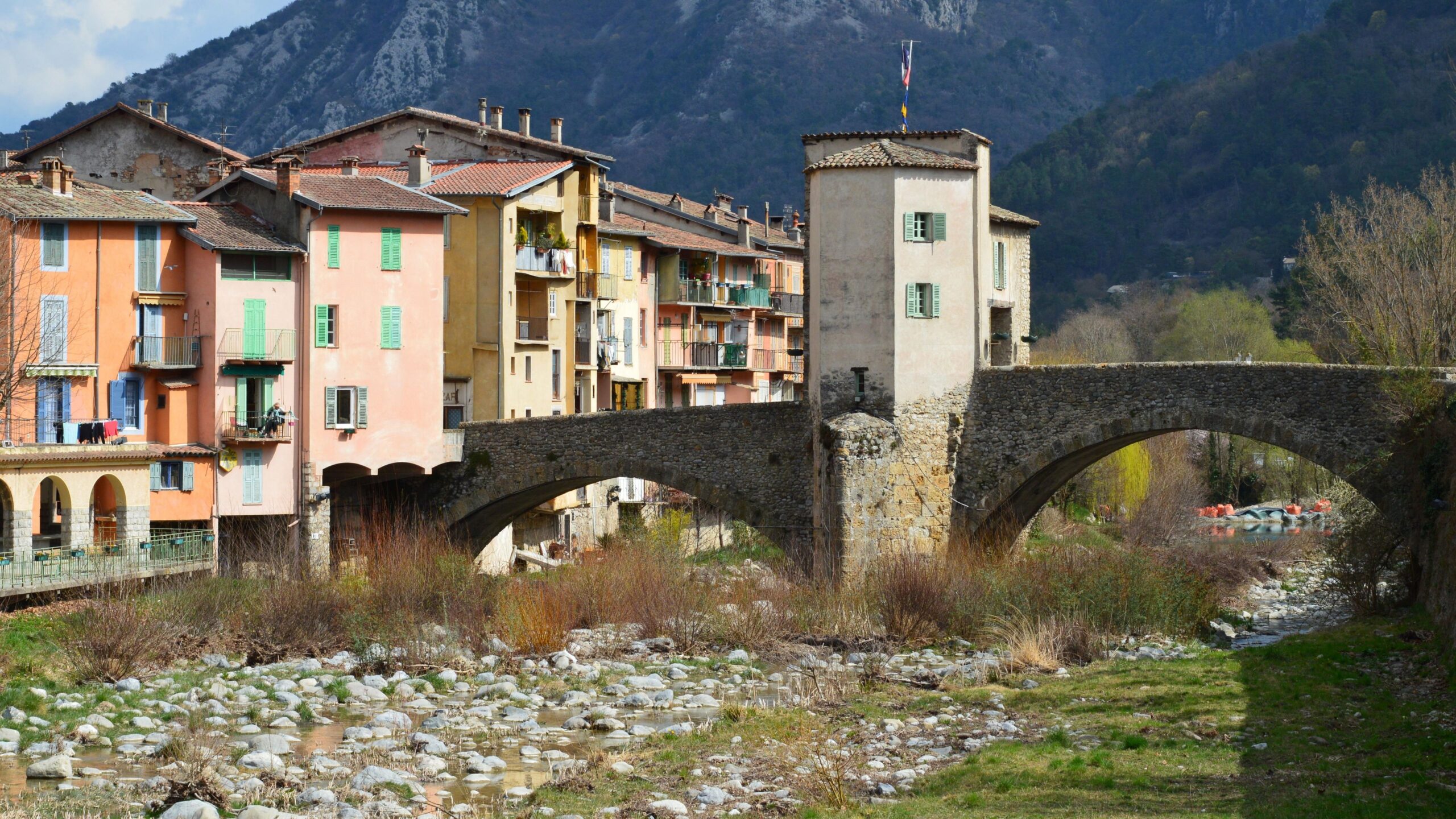 Colorful houses and Vieux Pont in Sospel, Provence, showcase historic architecture against a mountainous backdrop.