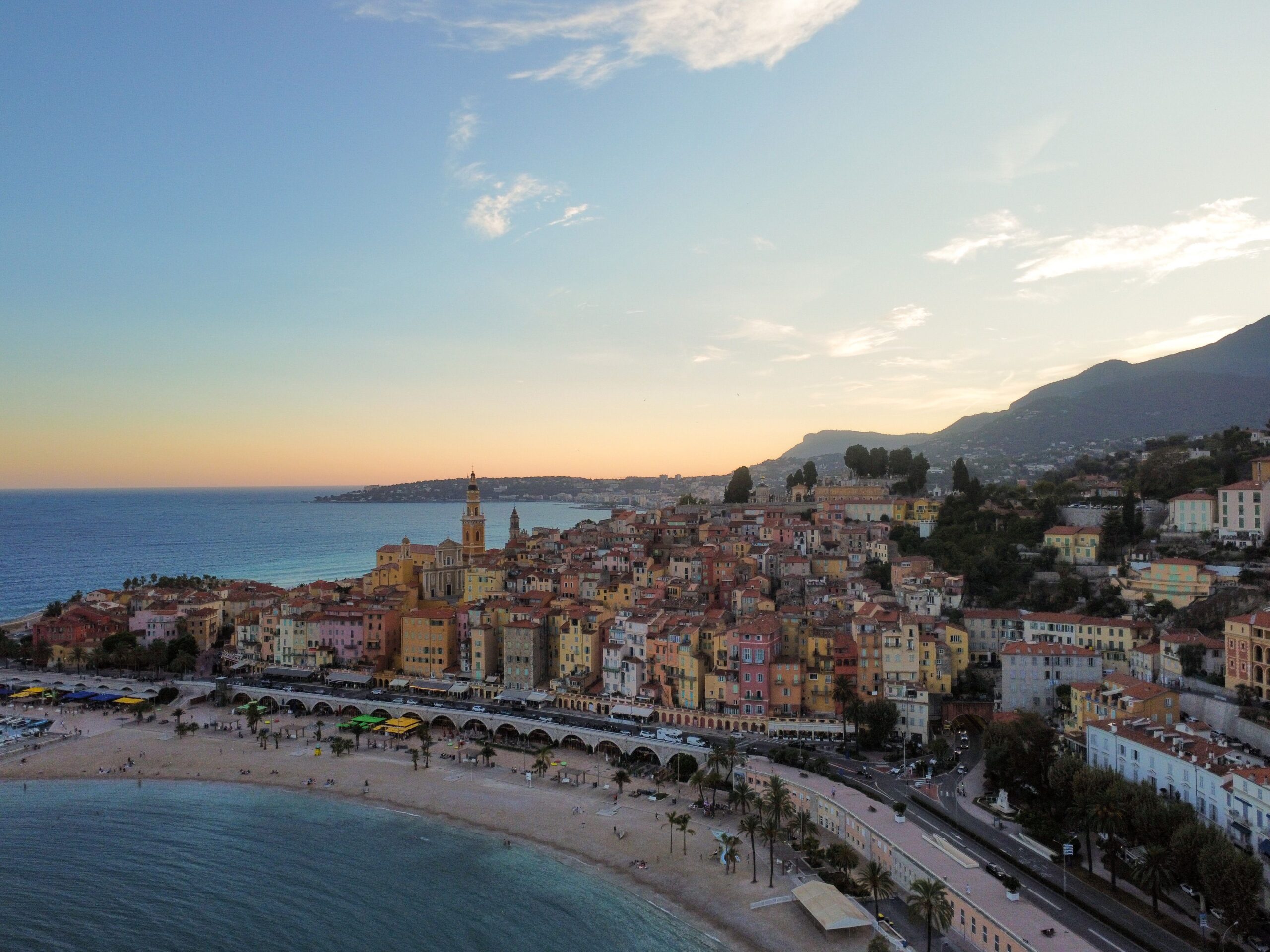 Breathtaking aerial view of Menton, France with colorful houses and coastline at sunset.