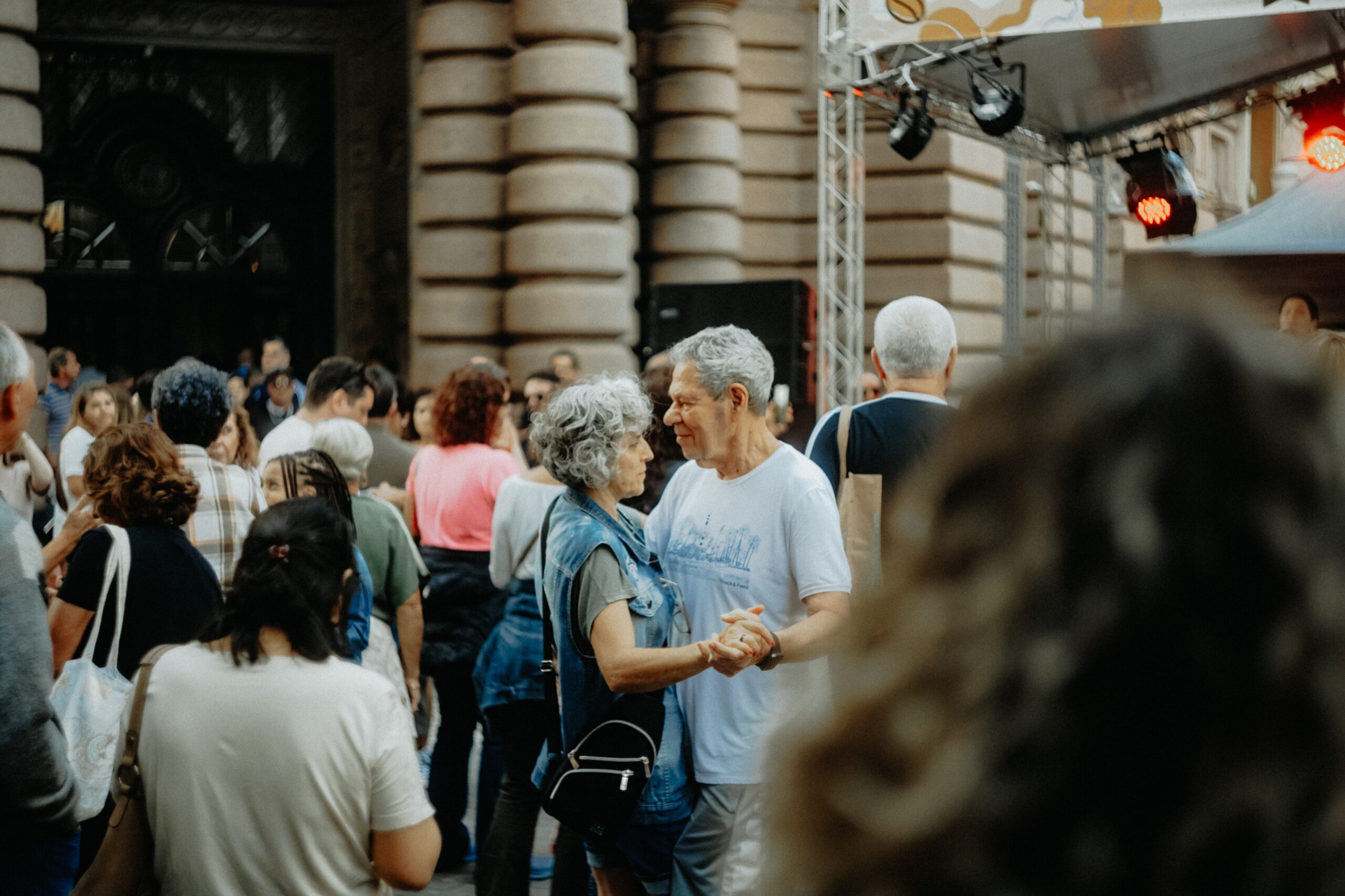 Charming scene of an elderly couple dancing amidst a lively crowd at a street festival.