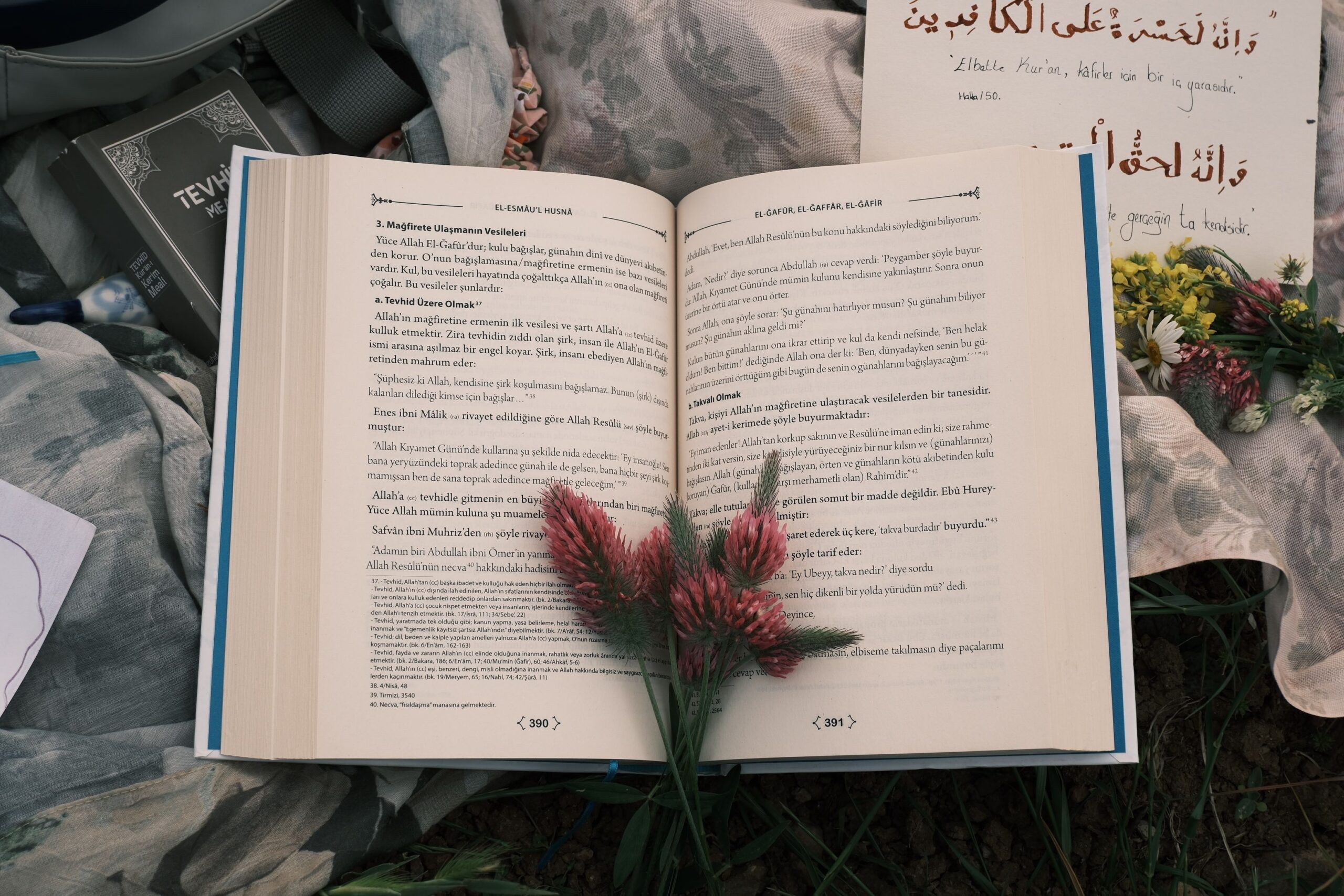 An open book with flowers placed on the pages, accompanied by handwritten notes and traditional script.