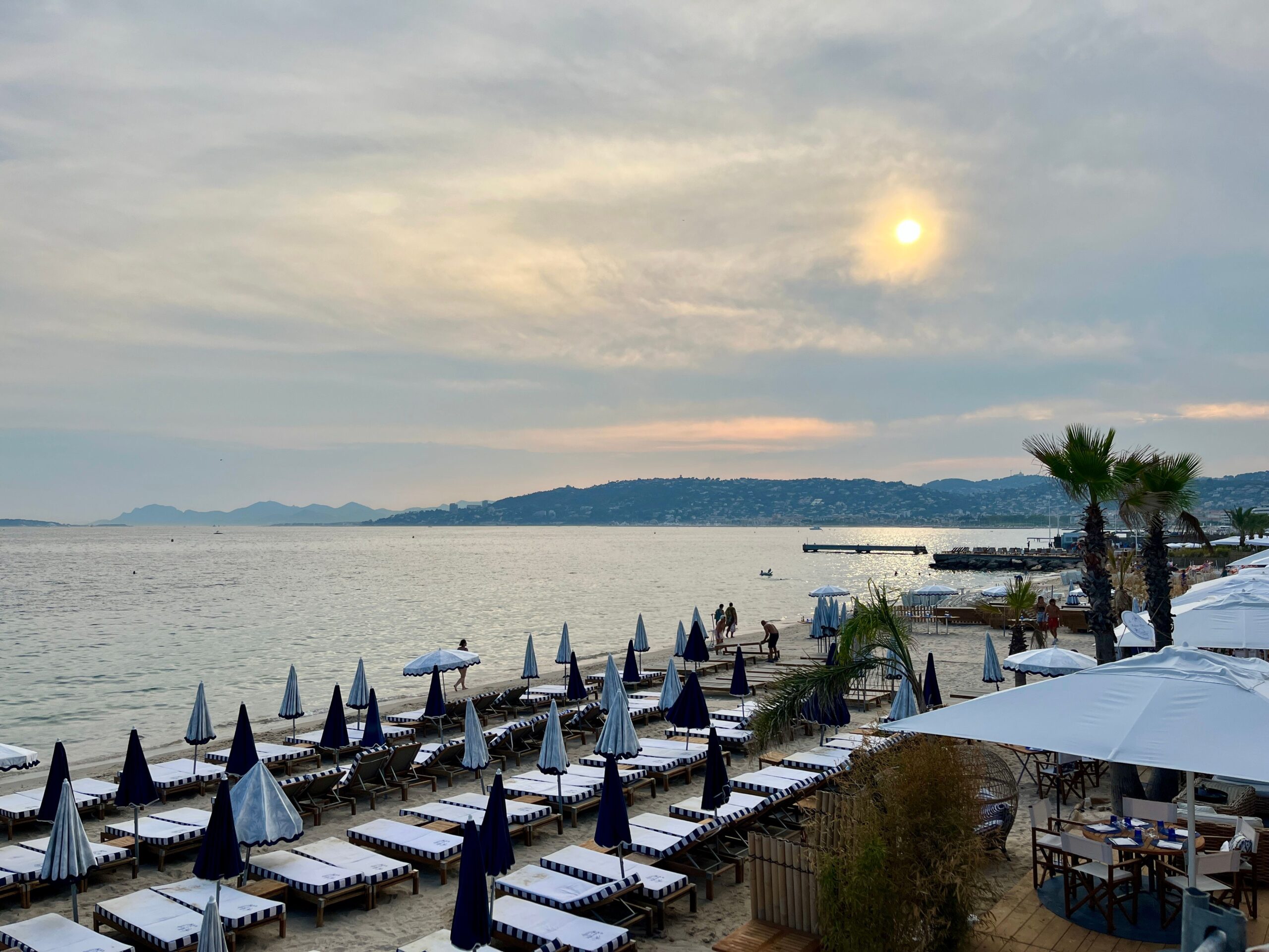 A tranquil beach scene at sunset with sunbeds and umbrellas overlooking the calm sea.