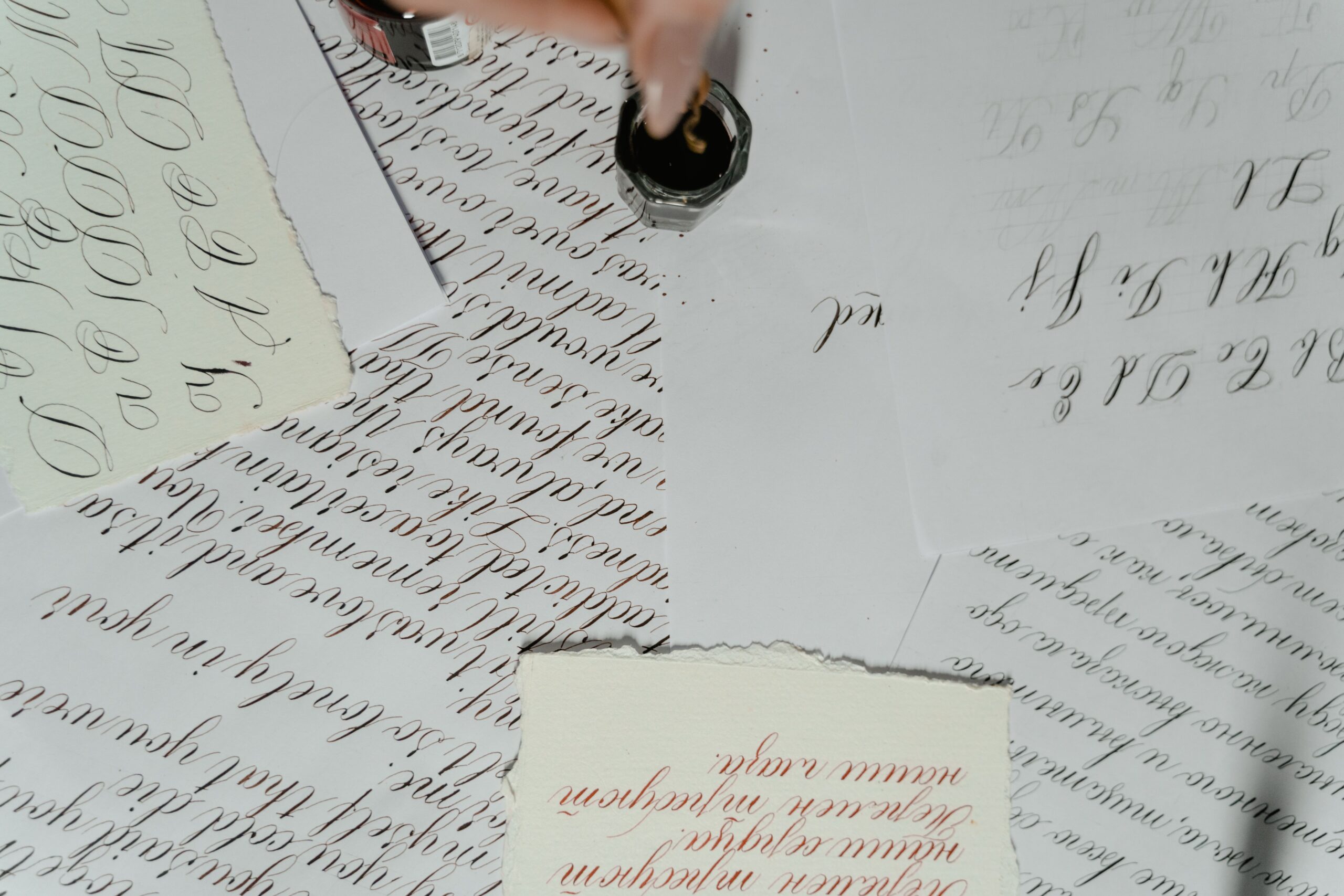Close-up of artistic calligraphy papers with elegant handwriting and ink jar.